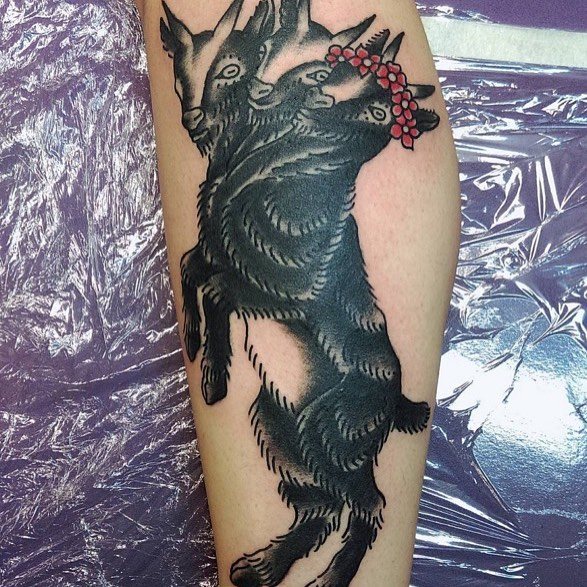 Tatouage noir d'une chèvre à trois têtes