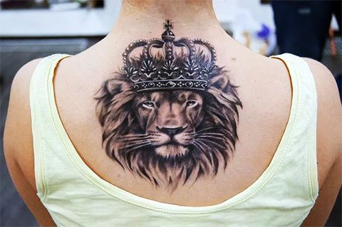 Tatouage d'un lion avec une couronne sur le dos de la fille