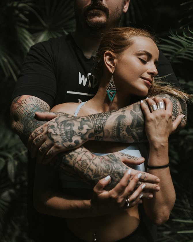 Homme aux bras tatoués serrant une femme dans ses bras