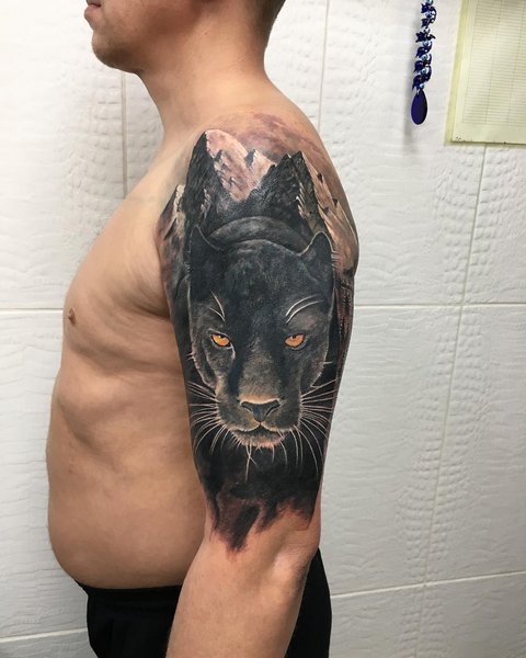 Tatouage masculin d'une panthère et de montagnes sur l'épaule