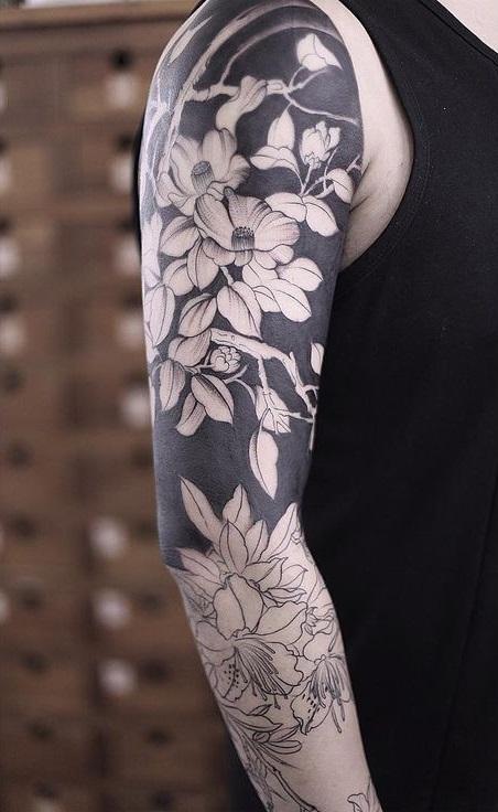 Tatouage d'homme sur le bras avec des motifs noirs et des fleurs
