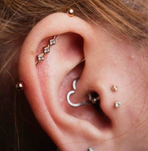 Cartilage d'oreille percé dans l'oreille d'une fille avec une boucle d'oreille, un clou de girofle, une chaîne
