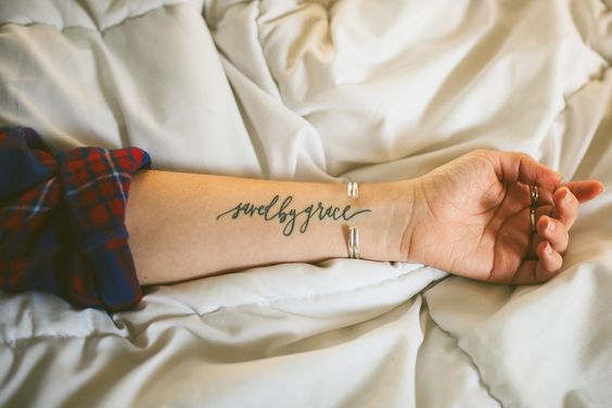 Sauvé par la grâce. Le script du tatouage est conçu par Juliet Grace Lapham.