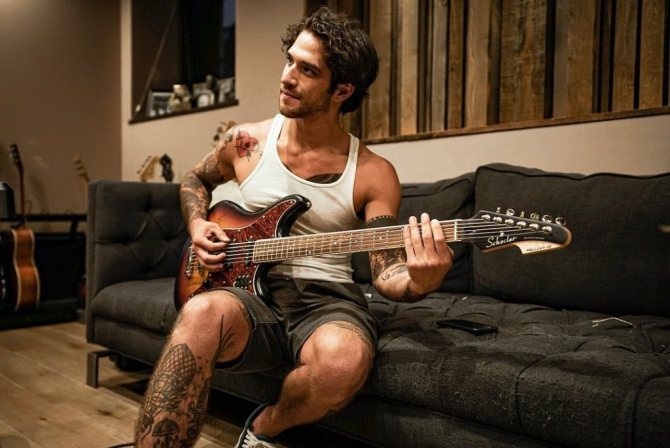 Tyler Posey est assis sur le canapé avec une guitare.