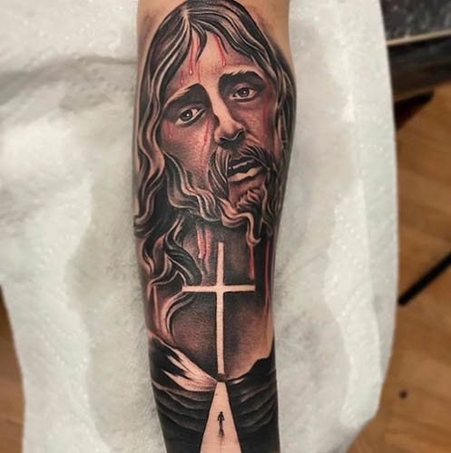 Tatouage de Jésus sur le bras, le dos, l'épaule, la poitrine. Signification, sur la croix, avec le diable, machine, colombe