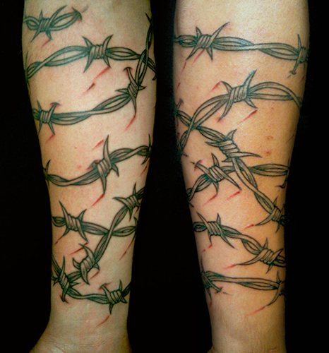 Tatouage de fil barbelé. Signification sur pied, poignet, cou, jambe, avec fleurs, rose, cœur, croix