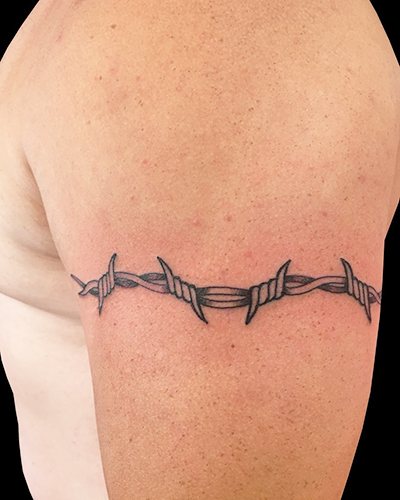 Tatouage de fil barbelé. Signification sur pied, poignet, cou, jambe, avec fleurs, rose, cœur, croix
