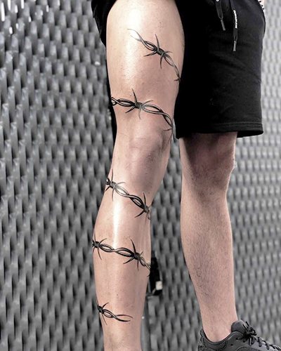 Tatouage de fil barbelé. Signification sur pied, poignet, cou, jambe, avec fleurs, rose, cœur, croix