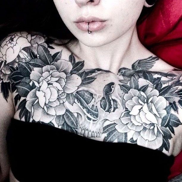 Tatouage sur la poitrine avec des fleurs et d'autres objets.
