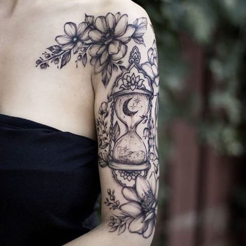 Tatouage de sablier et de fleurs sur le bras d'une fille