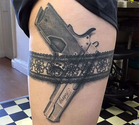 Tatouage d'un pistolet sur la cuisse d'une jeune fille