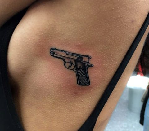 Tatouer un pistolet sur le côté d'une fille