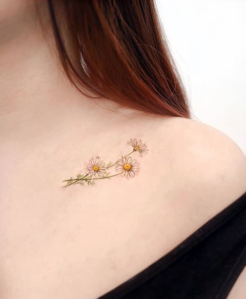Tatouage d'une marguerite sur la clavicule d'une fille