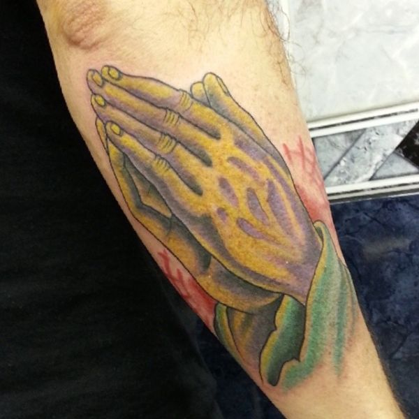 Tatouage de mains en prière sur l'avant-bras
