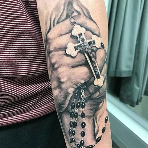 Tatouage de mains en prière avec une croix