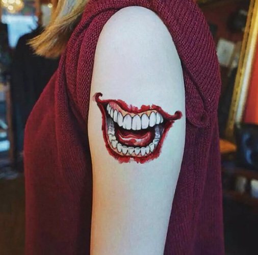 Tatouage du sourire du Joker sur son bras. Croquis, photos