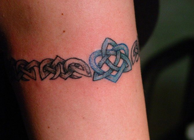 Tatouage autour du biceps homme, femme. Photo : dans le style slave, le motif scythe, les nœuds celtiques