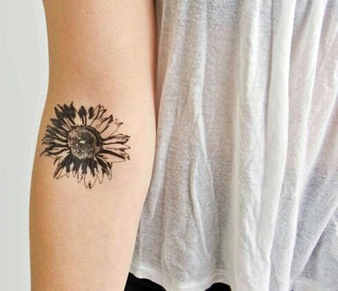 Tatouage d'une marguerite sur le bras d'une fille