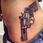 Tatouage avec un pistolet sur le côté d'une fille