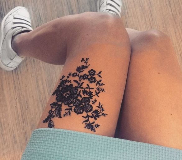 Tatouage en dentelle avec des fleurs sur la jambe d'une fille