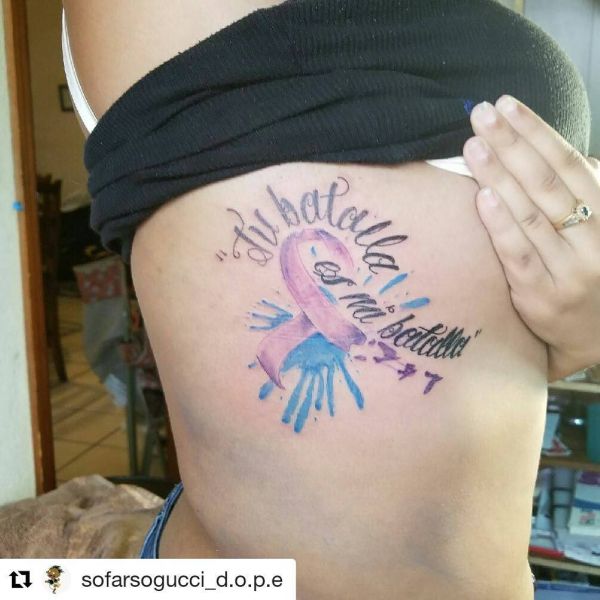 Tatouage en forme de ruban et inscription de style aquarelle sur le côté du corps d'une fille