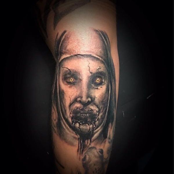 Tatouage diabolique d'un visage de grand-mère sur sa jambe.