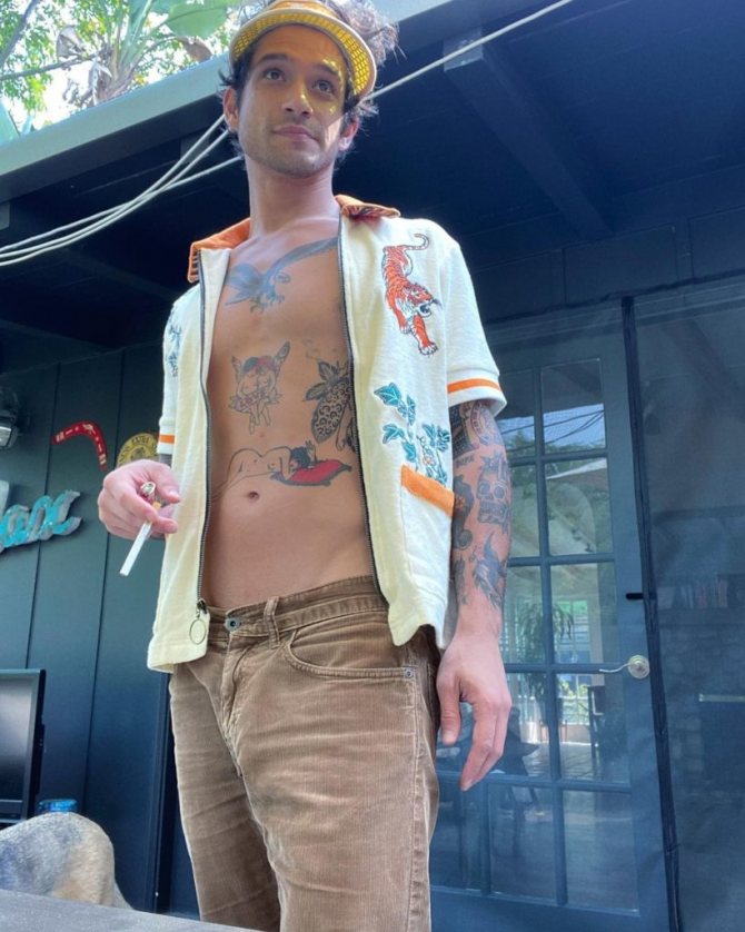 Tatouages de Tyler Posey sur la poitrine et le torse. Acteur en chemise ouverte.