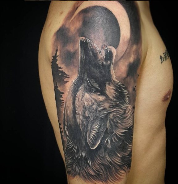 Loup hurlant à la lune - un tatouage de rockeur sur l'épaule