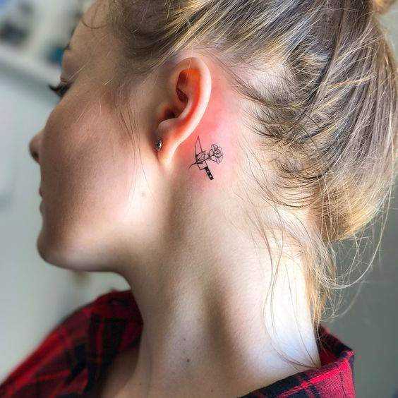 Tatouage derrière l'oreille, rose et couteau